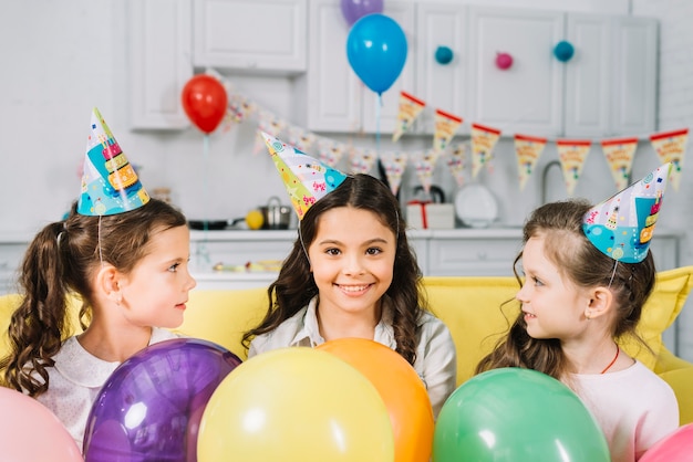 Girls looking at their happy friend with colorful balloons