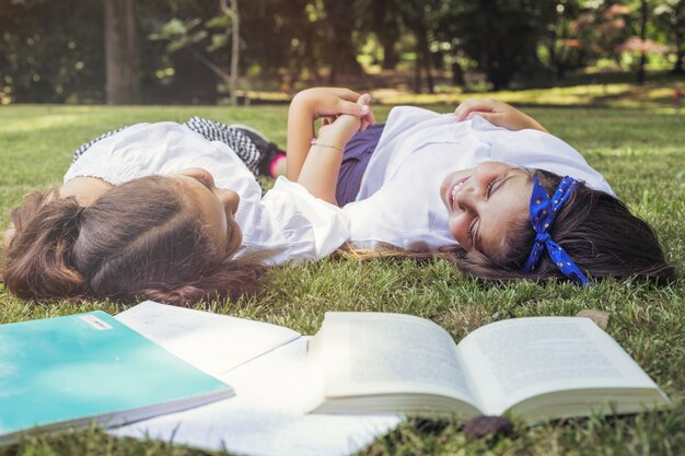 Girls lying on grass holding hands smiling