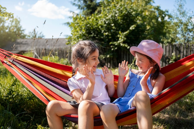 Girls playing outdoors together and sitting in hammock