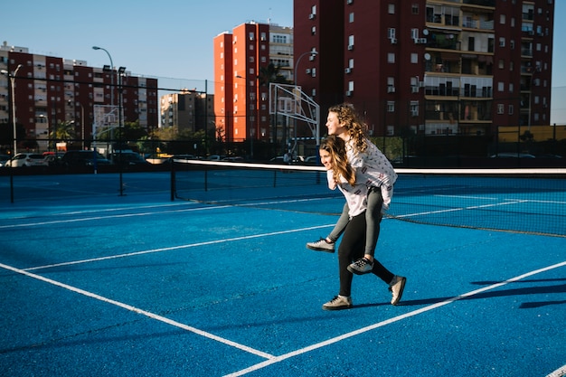 Girls playing on rooftop with blue tennis field