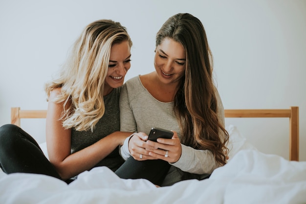 Девушки играют с телефоном в постели