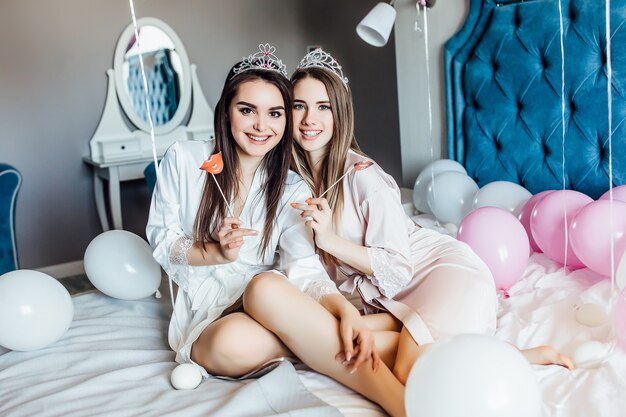 Girls sending an air kiss, looking at front with hen-party at home with balloons