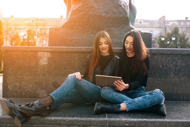 Free photo girls siiting in the floor looking a tablet