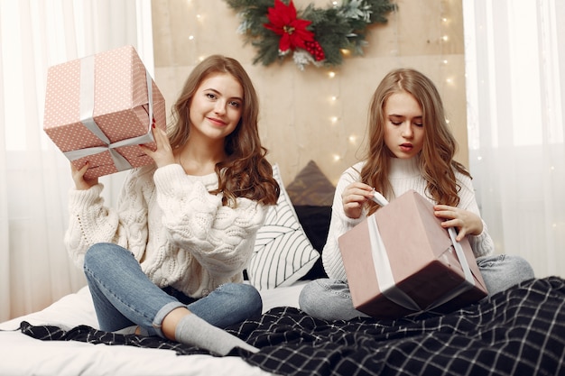 Девушки сидят на кровати. Женщины с подарочными коробками. Друзья готовятся к Рождеству.