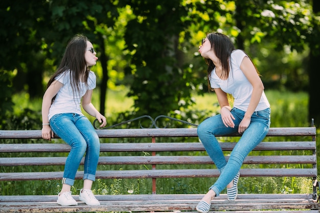 Ragazze sedute sul banco facendo facce