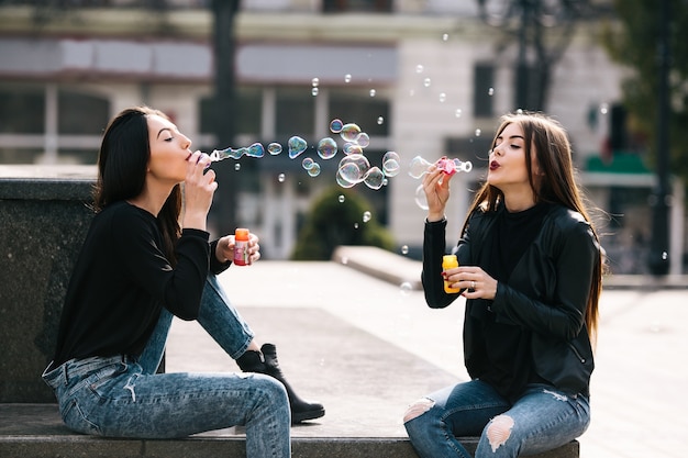 Girls sitting making bubbles of soap