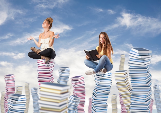 Foto gratuita ragazze che si siedono sulle montagne di libri