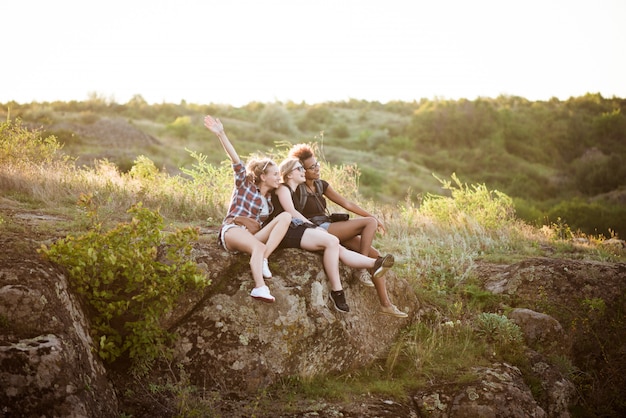 Девушки улыбаются, сидя на скале, наслаждаясь видом в каньоне