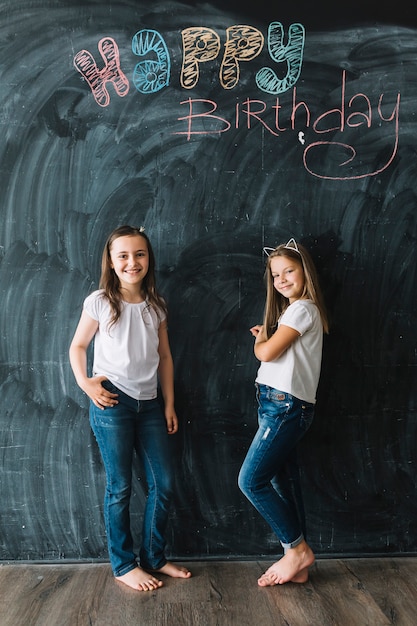 Free photo girls standing near happy birthday writing