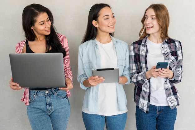 Girls standing with gadgets in hands and looking to each other