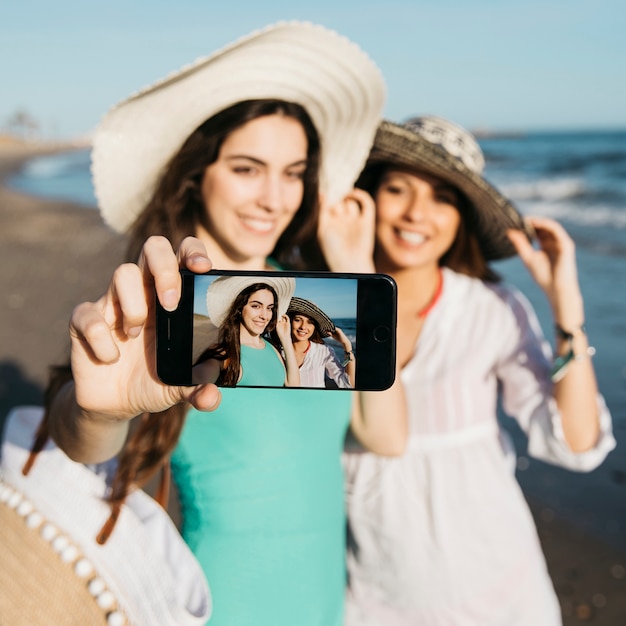 Foto gratuita ragazze che assumono selfie in spiaggia