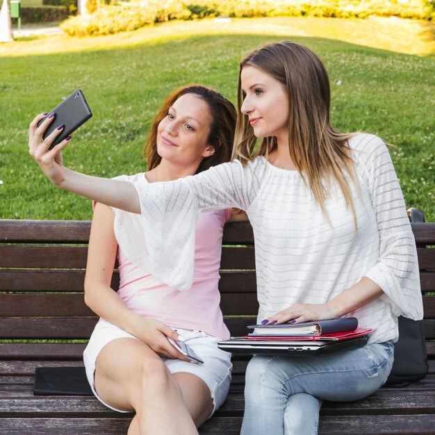 Girls taking selfie on bench