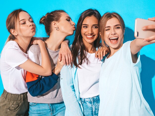 Girls taking selfie self portrait photos on smartphone.Models posing near blue wall in studio,Female showing positive face emotions