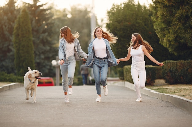 Бесплатное фото Девушки гуляют в весеннем городе с милой собакой