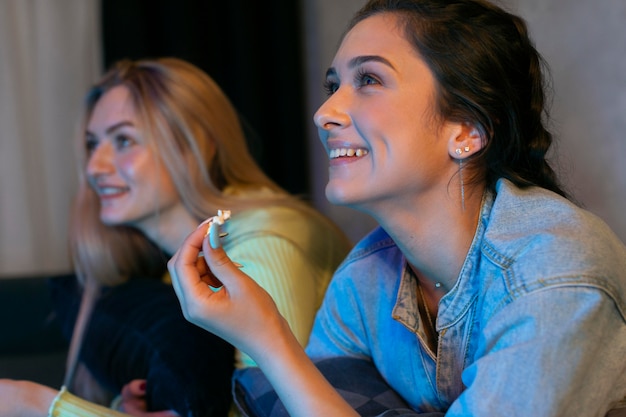 Foto gratuita ragazze che guardano il servizio di streaming insieme al chiuso