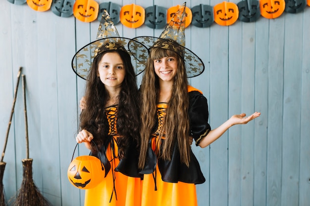 Girls in witch apparel standing in pointy hats and smiling