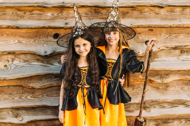 Девушки в костюмах ведьмы обнимаются и улыбаются