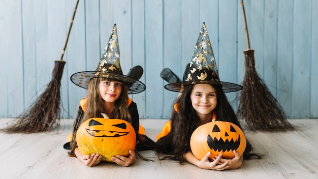 Girls in witch costumes lying with pumpkins