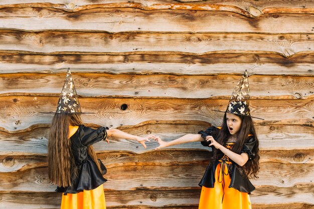 Girls in witch costumes with reach out hands looking each other 