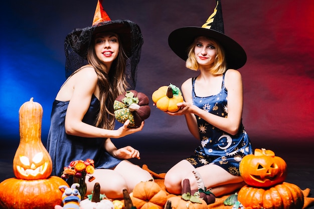 Girls in witch hats holding pumpkins