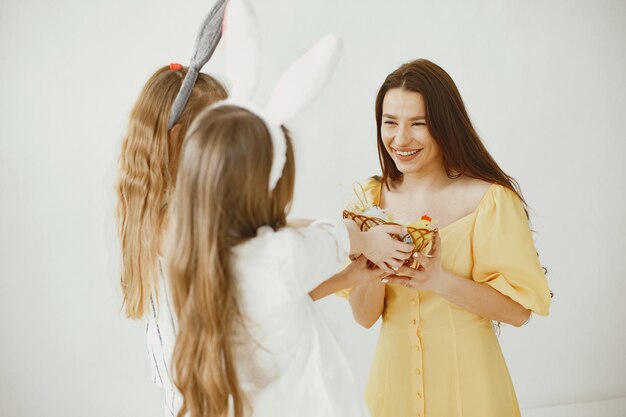 Girls with a basket of eggs. Happy mom in a yellow dress. Long hair in girls.