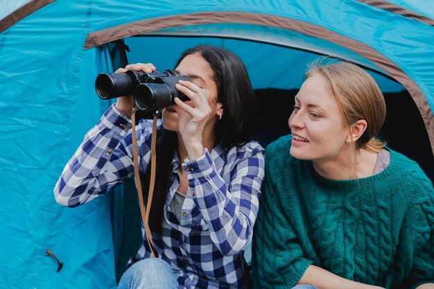 Девушки с биноклем, сидящие в палатке