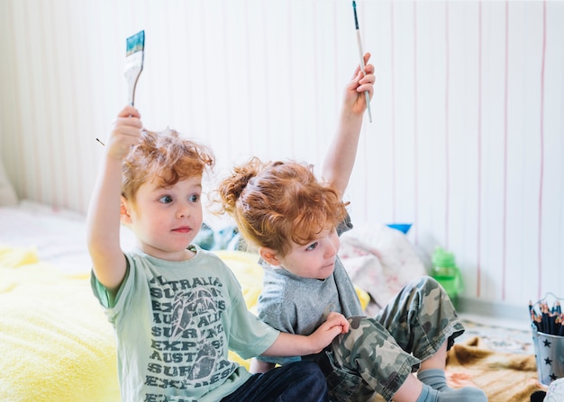 Free photo girls with brushes in upped hands sitting on floor