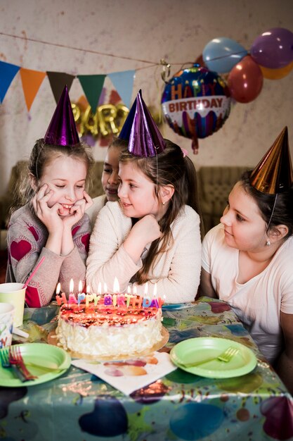 Girls with party hats near cake