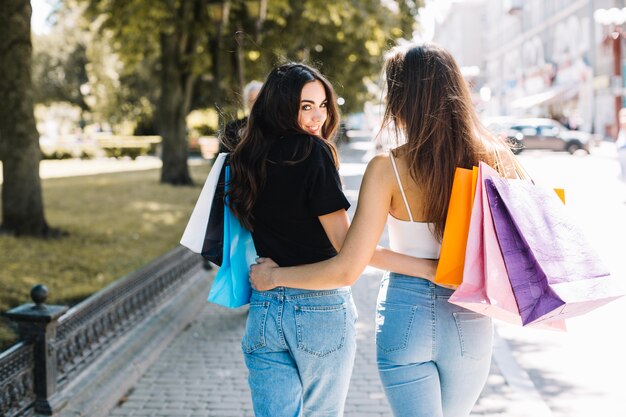 Girls with shopping bags walking in park