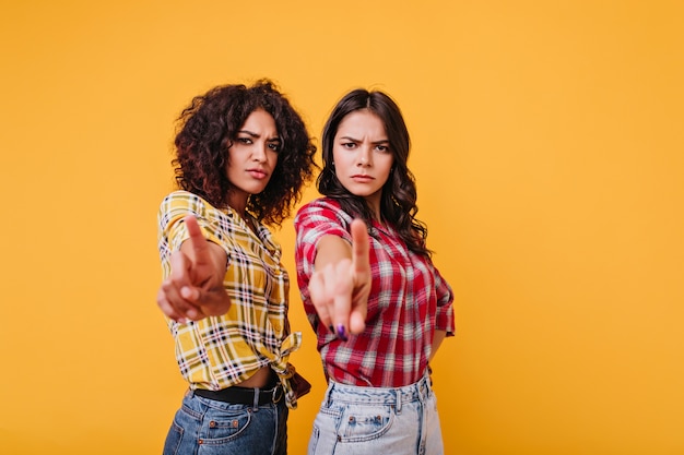 Foto gratuita le ragazze con l'espressione del viso severo mostrano il segnale di stop. le amiche guardano con rimprovero, mostrando le dita indice