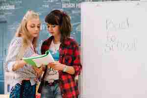 Free photo girls with textbook at whiteboard