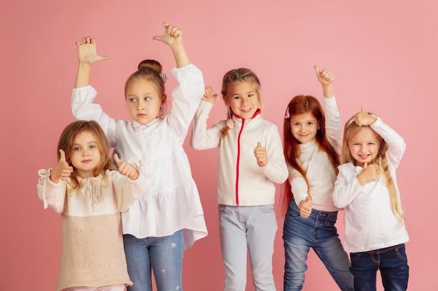 Dare e ricevere regali durante le vacanze di natale. gruppo di bambini sorridenti felici divertendosi, celebrando isolato su sfondo rosa studio. incontro di capodanno 2021, infanzia, felicità, emozioni.
