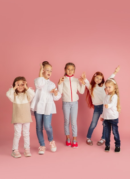 Giving and getting presents on Christmas holidays. Group of happy smiling children having fun, celebrating isolated on pink studio background. New Year 2021 meeting, childhood, happiness, emotions.