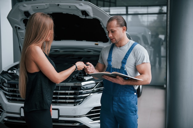 Giving keys. Results of repair. Confident man showing what kind of damage her car was taken