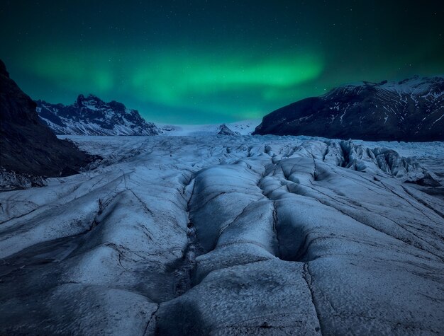 Glacier at night with an aurora borealis in the sky.