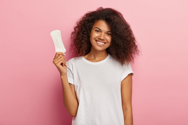 Glad attractive curly female model holds thin sanitary pad