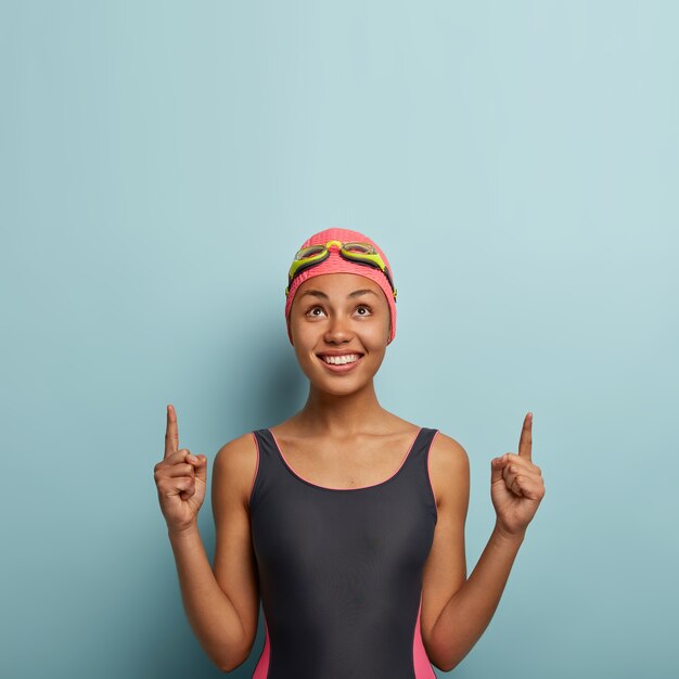 Glad attractive female swimmer posing with goggles