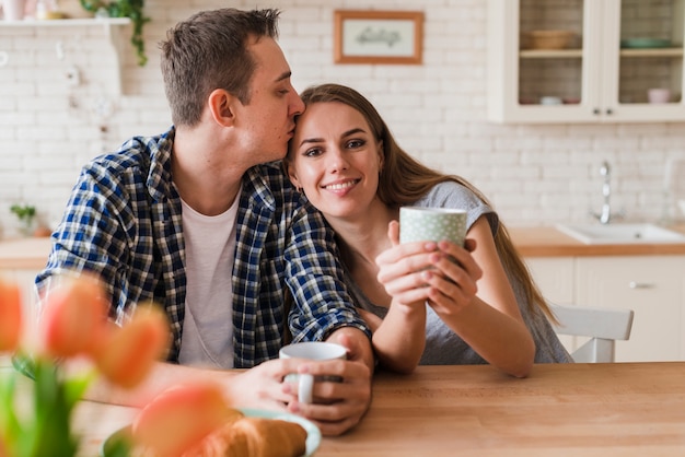 喜んでカップルがキスをし、テーブルでお茶を楽しんで