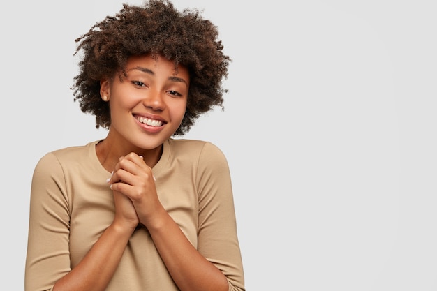 Felice ragazza dalla pelle scura ha un'espressione facciale positiva