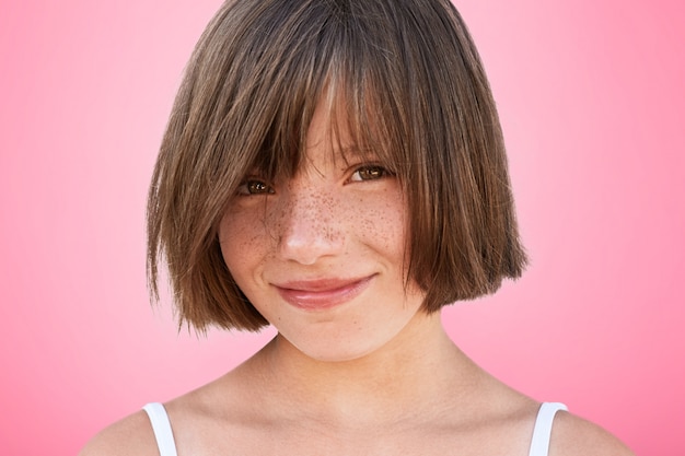 Glad delightful smiling cheerful little kid with bobbed hairstyle looks happily at camera, rejoices spending free time with parents who bought her new toy. Pretty adorable girl poses in studio