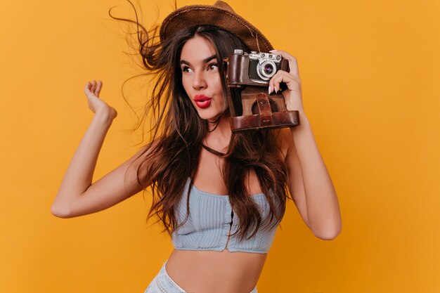 Glad girl with long hairstyle holding camera and waving hand