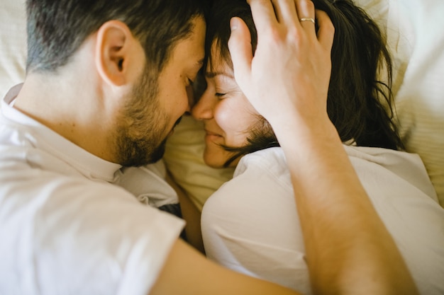 Glad husband and wife hugging in bed