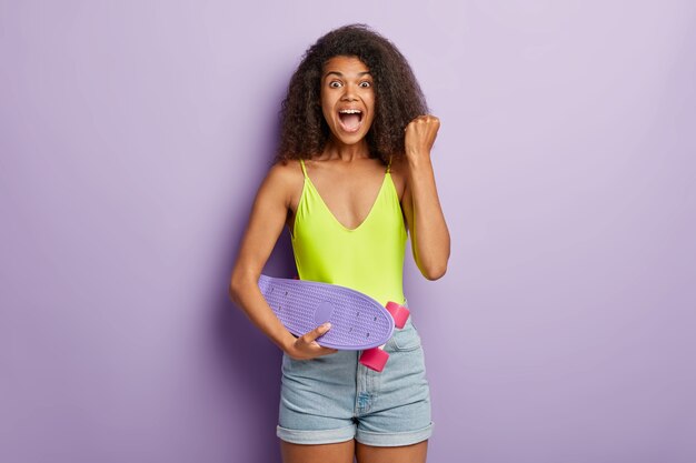 Glad joyful sportive female posing with skateboard