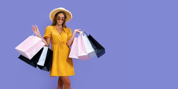Glad woman in hat and sunglasses holds purchases while smiling at camera black friday big sales