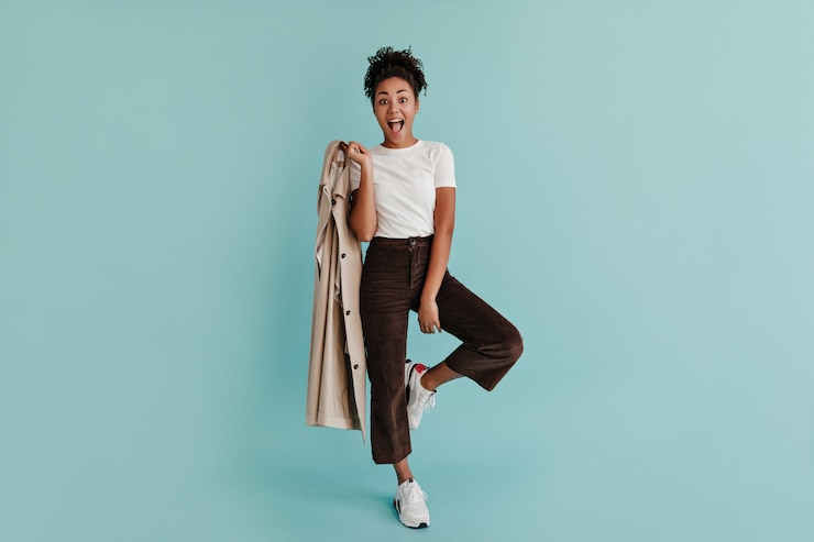 Free Photo glad woman with trench coat standing on one leg