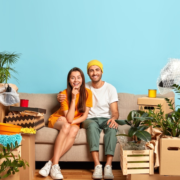 Glad young couple sitting on the couch surrounded by boxes