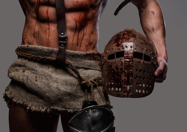 Gladiator with muscular body holding a helmet