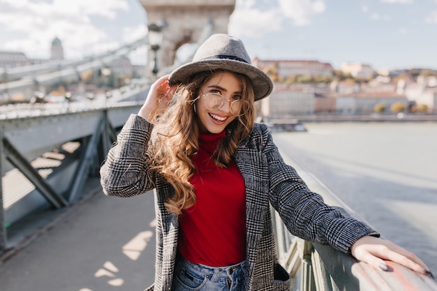 Glamorous european girl in red sweater spending leisure time outdoor in sunny autumn day