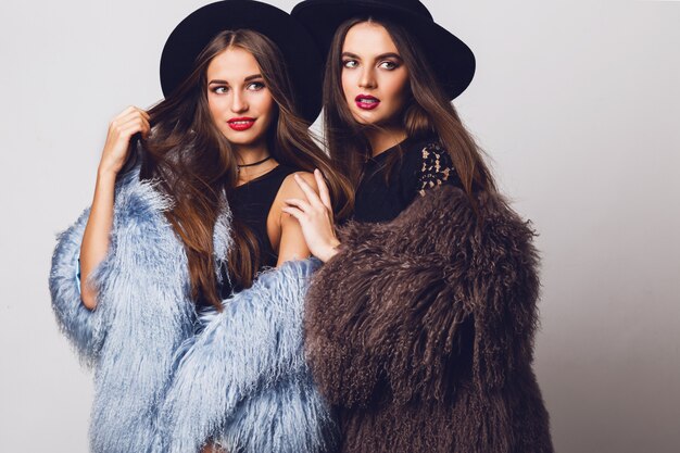 Glamorous pretty women posing and wearing fur coats