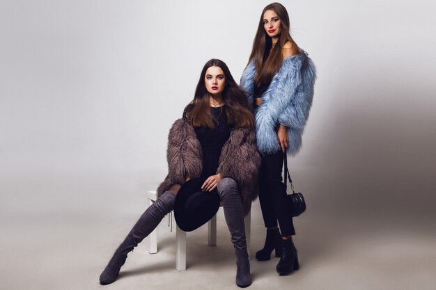 Glamorous pretty women posing and wearing fur coats